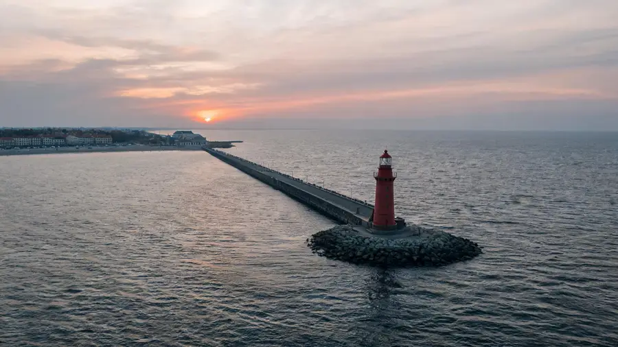 Latarnia i falochron w Kołobrzegu o zachodzie, kadr spoza strefy portu